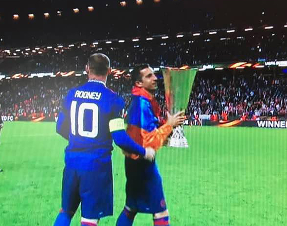 Draped in the Armenian tri-color, Henrikh Mkhitaryan carries the UEFA Europa League trophy on the field