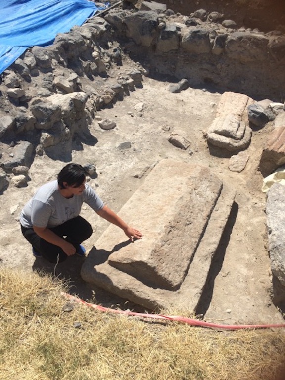 Mary Safaryan pointing to a tombstone with Armenina writing