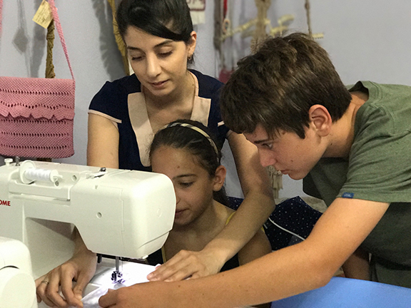 Joseph teaching a student how to use the sewing machine