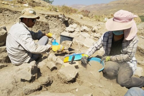 Two HKU students uncover the collapsed top of an ancient wall at the Vedi Fortress, with the mountains of the Vedi River valley visible in the background. Photo Credit: The University of Hong Kong