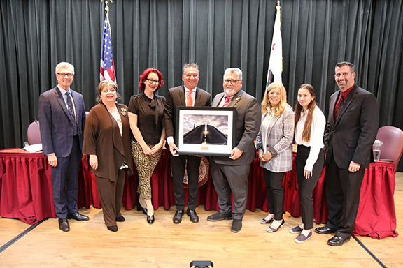Dr. Vahe Peroomian (center) presents State Senator Anthony Portantino with a photograph of Dzidzernagapert, which he took, as appreciation for the senator spearheading the passage of measure allowing GCC to close on April 24.